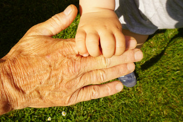 Kind greift die Hand einer älteren Person